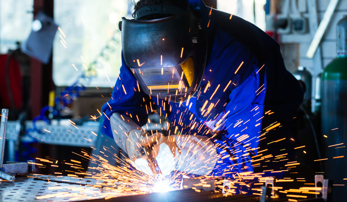 welding man sparks flying around protective face mask in a shop