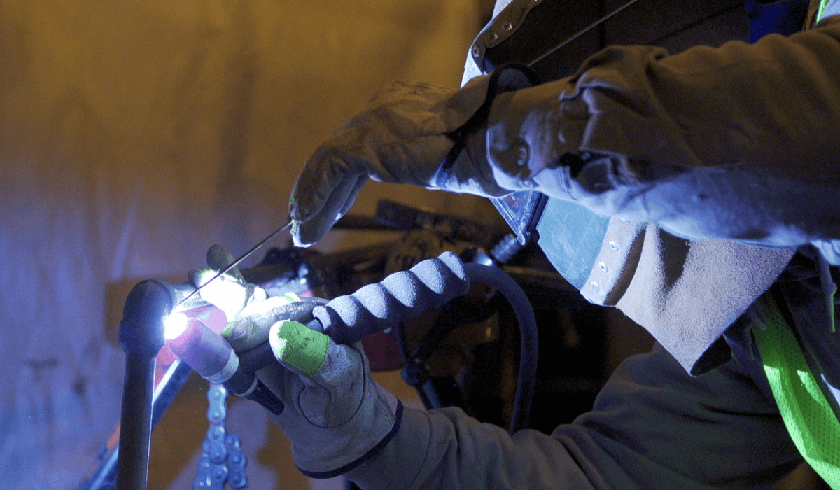 ParFab worker with gloves and mask doing technical mechanical work.